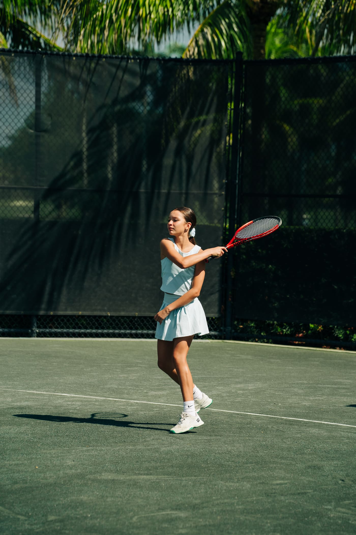 Junior in a white dress holding serve