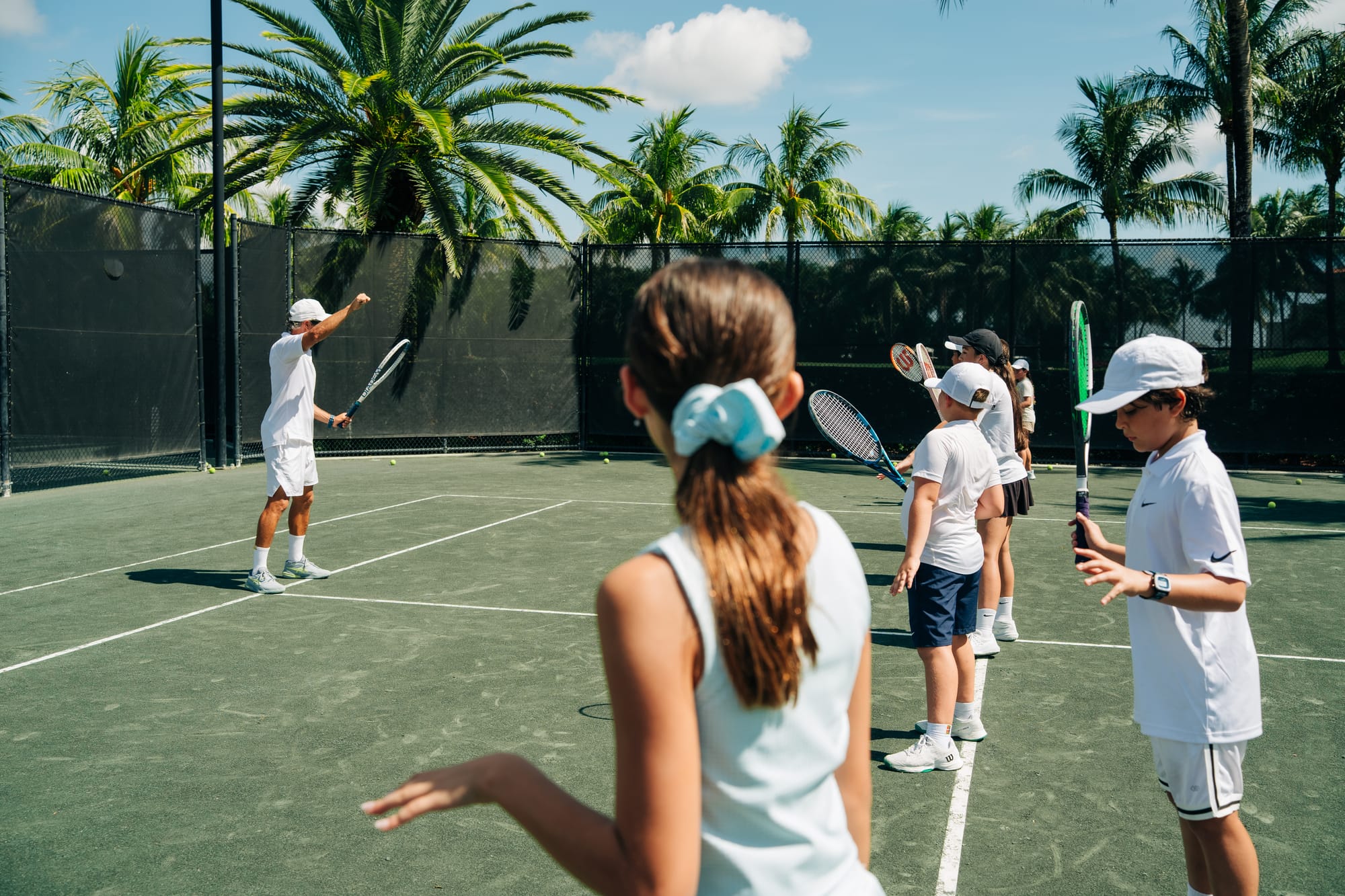 Junior watching a group lesson from the baseline